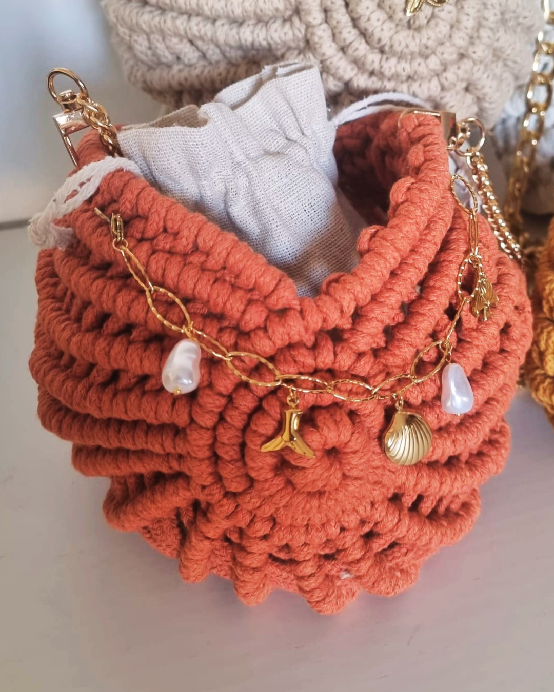 Bolsa Búzio Terracota - detalhe dos charms dourados e pérolas