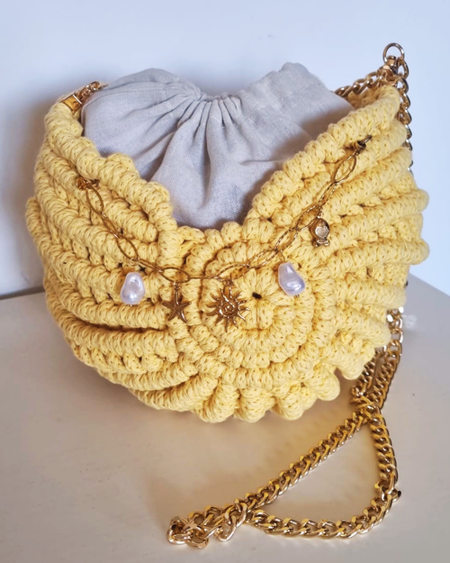 Bolsa Búzio Amarelo Manteiga - detalhe dos charms: estrela do mar e sol dourado com pérolas barrocas