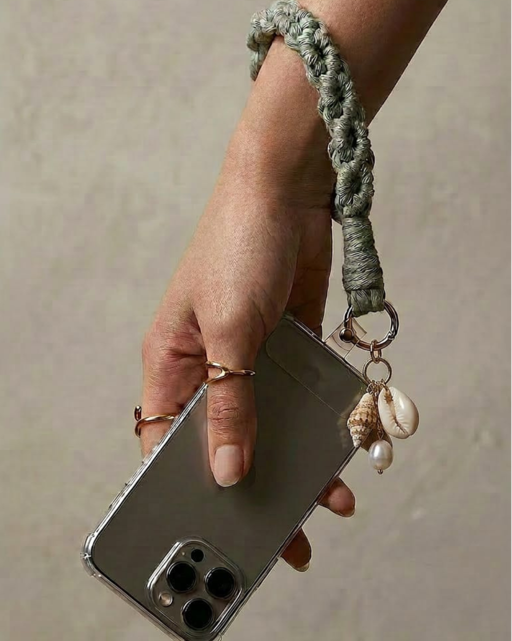 Pulseira de telemovel macramé verde sage com charms de búzio e concha - modelo a usar